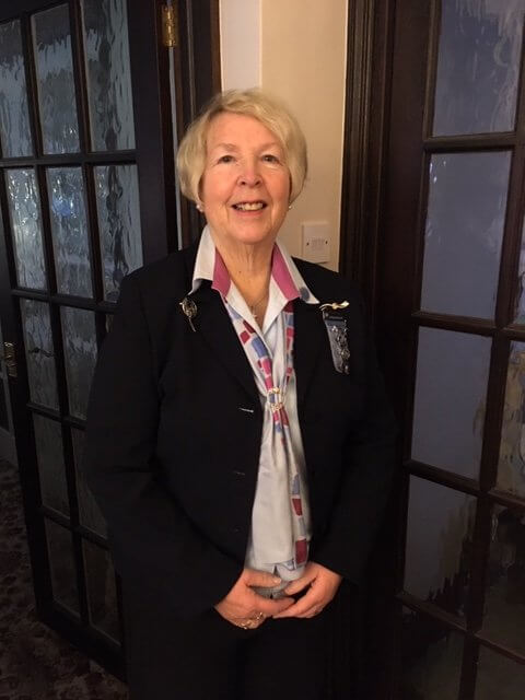 Awards Chair Carol Roberts stands in front of a door
