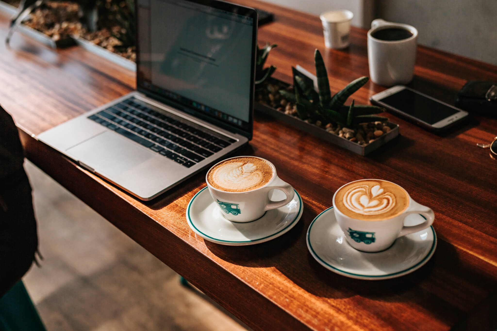 Two cups of coffee in front of a laptop